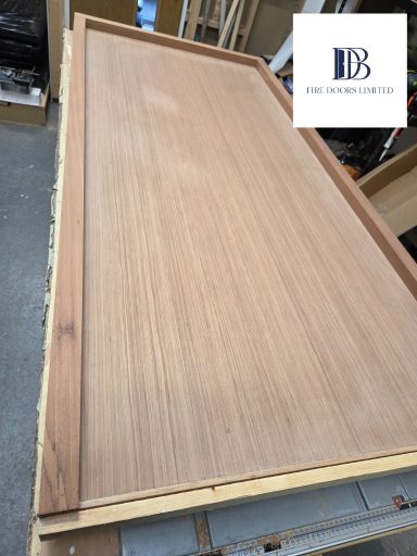 Unfinished oak veneer flush FD30 fire door blank, ready for final trimming and finishing.